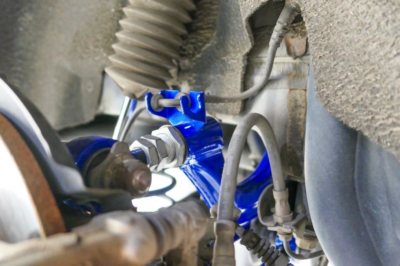 Close-up of a vehicle suspension system with a blue control arm.