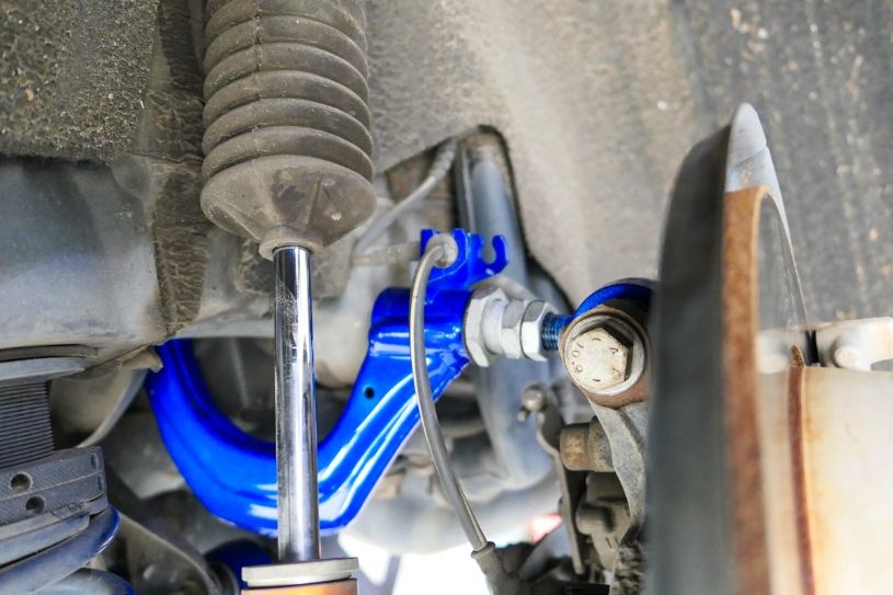 Close-up of a car suspension system with a blue control arm and metal components.